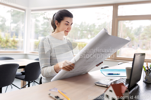 Image of young woman with blueprint working at home office