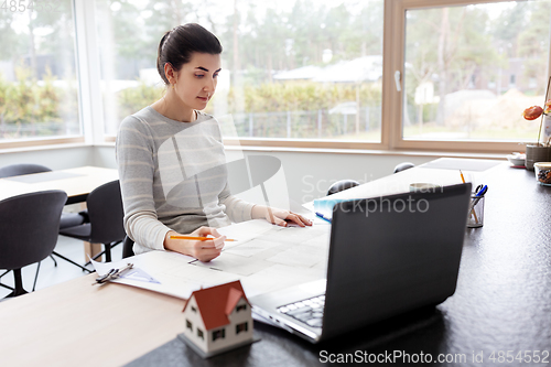 Image of young woman with blueprint working at home office