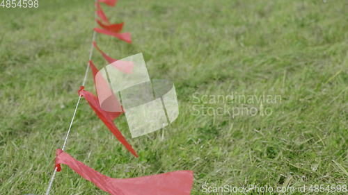 Image of Red flags fluttering in the wind, against a background of green grass