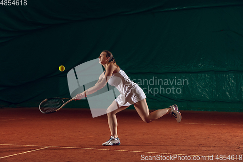 Image of Young caucasian professional sportswoman playing tennis on sport court background
