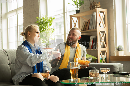 Image of Excited family watching football, sport match at home, beautiful couple