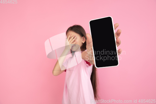 Image of Caucasian little girl portrait isolated on pink studio background, emotions concept