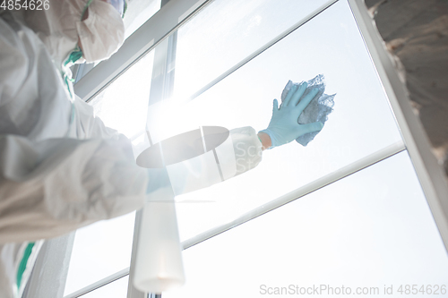 Image of Coronavirus Pandemic. A disinfector in a protective suit and mask sprays disinfectants in the house or office