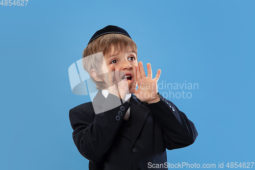 Image of Portrait of a young orthodox jewish boy isolated on blue studio background, meeting the Passover