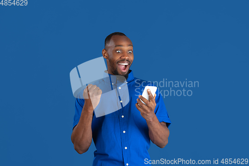 Image of Monochrome portrait of young african-american man on blue studio background