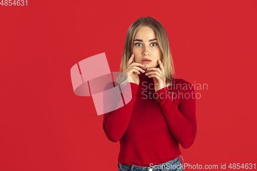 Image of Monochrome portrait of young caucasian blonde woman on red background