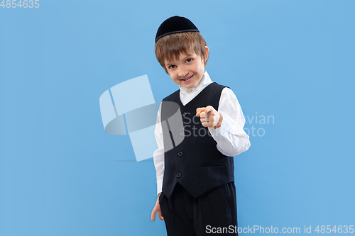 Image of Portrait of a young orthodox jewish boy isolated on blue studio background, meeting the Passover