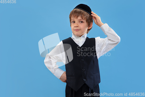 Image of Portrait of a young orthodox jewish boy isolated on blue studio background, meeting the Passover