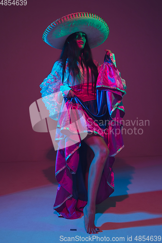 Image of Fabulous Cinco de Mayo female dancer on purple studio background in neon light