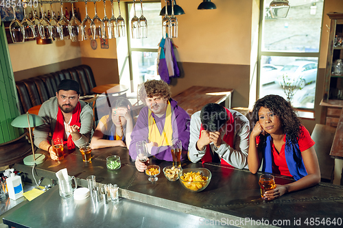 Image of Sport fans cheering at bar, pub and drinking beer while championship, competition is going