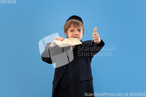 Image of Portrait of a young orthodox jewish boy isolated on blue studio background, meeting the Passover