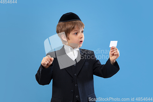 Image of Portrait of a young orthodox jewish boy isolated on blue studio background, meeting the Passover