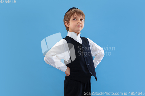 Image of Portrait of a young orthodox jewish boy isolated on blue studio background, meeting the Passover