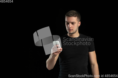 Image of Monochrome portrait of young caucasian man on black studio background