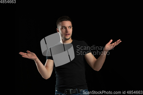 Image of Monochrome portrait of young caucasian man on black studio background