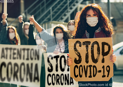 Image of Young people in face masks protesting of stop coronavirus pandemic on the street