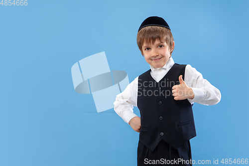 Image of Portrait of a young orthodox jewish boy isolated on blue studio background, meeting the Passover