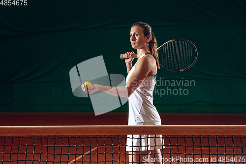 Image of Young caucasian professional sportswoman playing tennis on sport court background