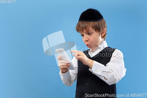 Image of Portrait of a young orthodox jewish boy isolated on blue studio background, meeting the Passover