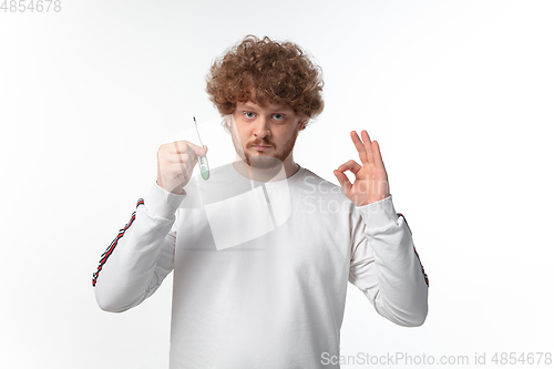 Image of How coronavirus changed our lives. Young man checking, taking temperature on white background