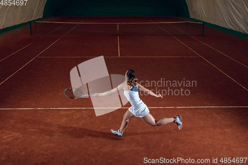 Image of Young caucasian professional sportswoman playing tennis on sport court background
