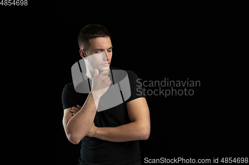 Image of Monochrome portrait of young caucasian man on black studio background