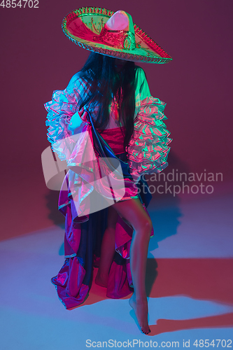 Image of Fabulous Cinco de Mayo female dancer on purple studio background in neon light