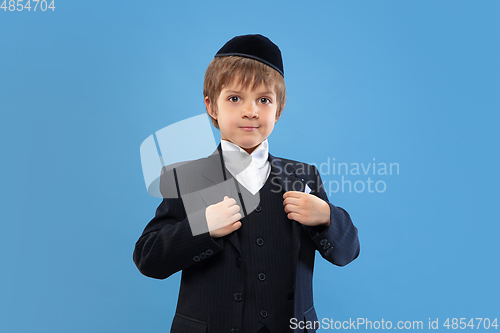 Image of Portrait of a young orthodox jewish boy isolated on blue studio background, meeting the Passover