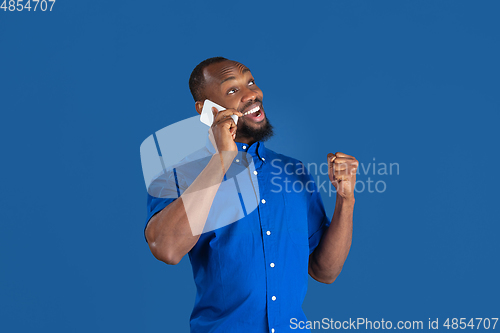 Image of Monochrome portrait of young african-american man on blue studio background