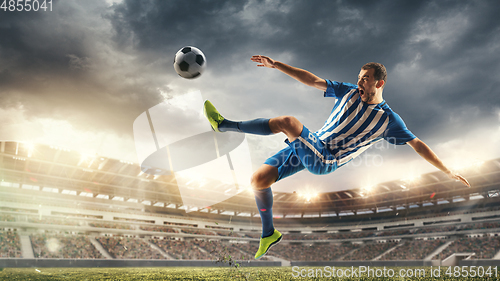 Image of Male football or soccer player at stadium - motion, action, activity concept