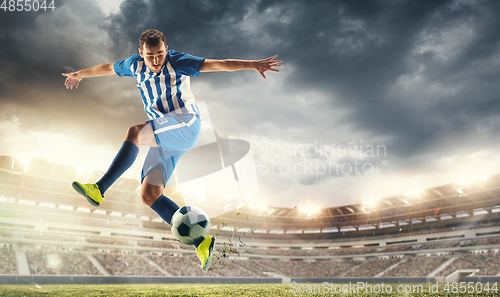 Image of Male football or soccer player at stadium - motion, action, activity concept