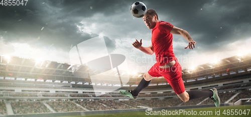 Image of Male football or soccer player at stadium - motion, action, activity concept