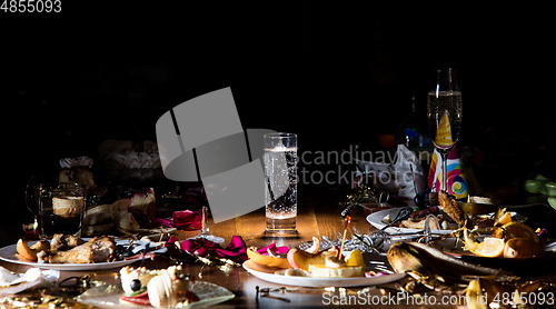 Image of Early morning after the party. Glass of pure, cold water on the table with confetti and serpentine, leftovers, flower petals