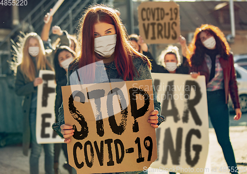 Image of Young people in face masks protesting of stop coronavirus pandemic on the street