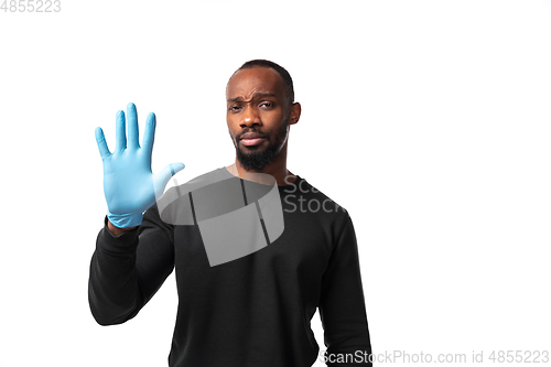 Image of How coronavirus changed our lives. Young man holding thermometer, taking temperature on white background