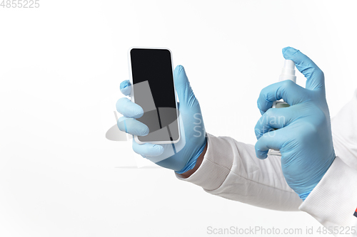 Image of How coronavirus changed our lives. Young man disinfecting gadgets surfaces on white background