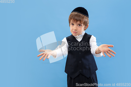 Image of Portrait of a young orthodox jewish boy isolated on blue studio background, meeting the Passover