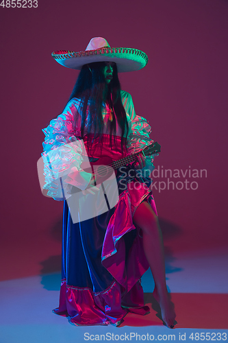 Image of Fabulous Cinco de Mayo female dancer on purple studio background in neon light