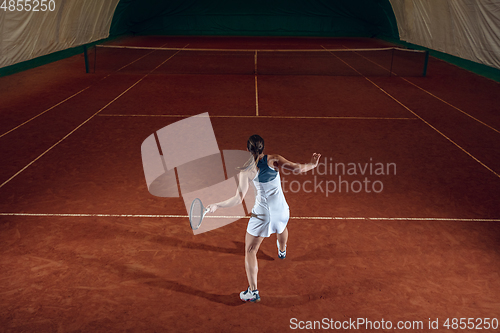 Image of Young caucasian professional sportswoman playing tennis on sport court background