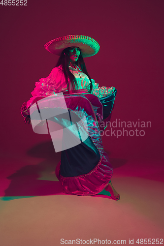 Image of Fabulous Cinco de Mayo female dancer on purple studio background in neon light