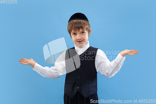 Image of Portrait of a young orthodox jewish boy isolated on blue studio background, meeting the Passover