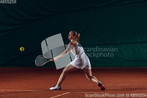 Image of Young caucasian professional sportswoman playing tennis on sport court background