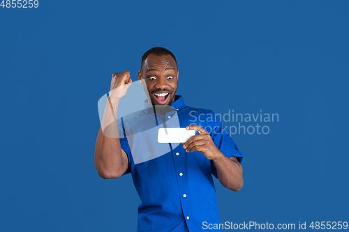 Image of Monochrome portrait of young african-american man on blue studio background