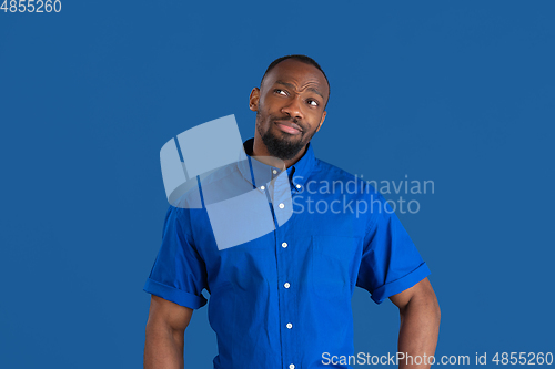 Image of Monochrome portrait of young african-american man on blue studio background