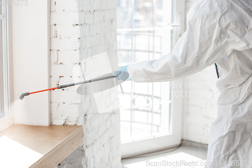 Image of Coronavirus Pandemic. A disinfector in a protective suit and mask sprays disinfectants in the house or office