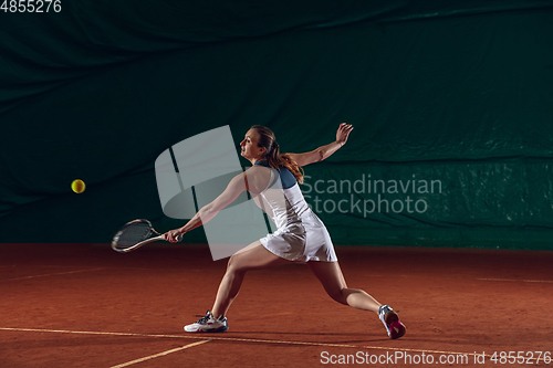 Image of Young caucasian professional sportswoman playing tennis on sport court background