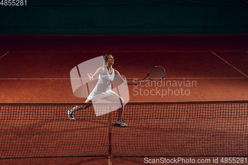 Image of Young caucasian professional sportswoman playing tennis on sport court background