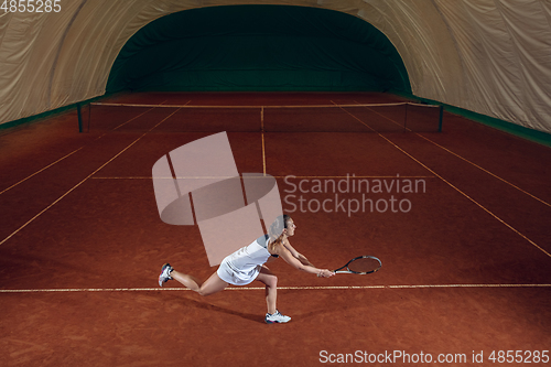 Image of Young caucasian professional sportswoman playing tennis on sport court background