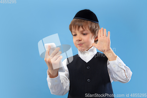 Image of Portrait of a young orthodox jewish boy isolated on blue studio background, meeting the Passover