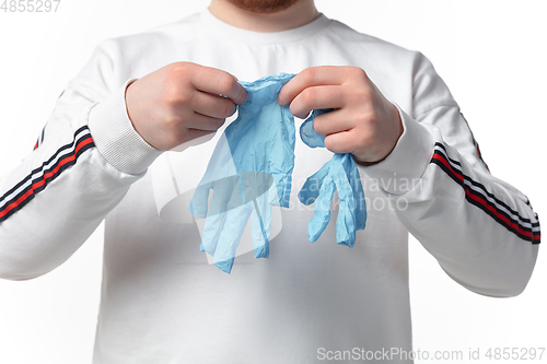 Image of How coronavirus changed our lives. Young man wearing protective gloves on white background